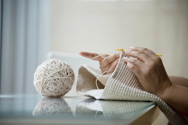 Woman crocheting in a cozy corner, feeling relaxed and stress-free
